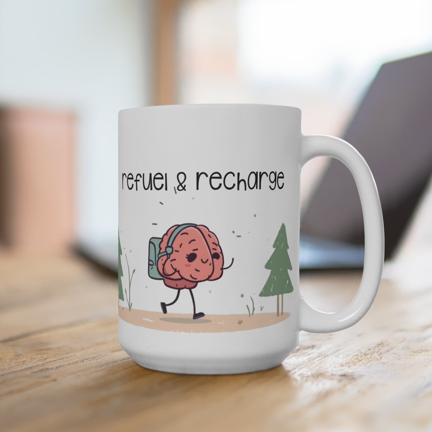 White mug with a cartoon brain character and 'refuel & recharge' text on a wooden surface.