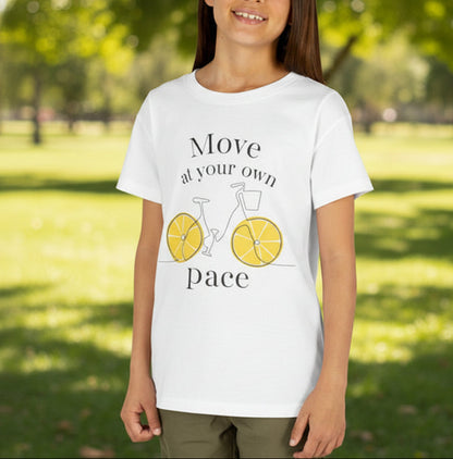 Young person wearing a white t-shirt with a bicycle graphic and text in a park.