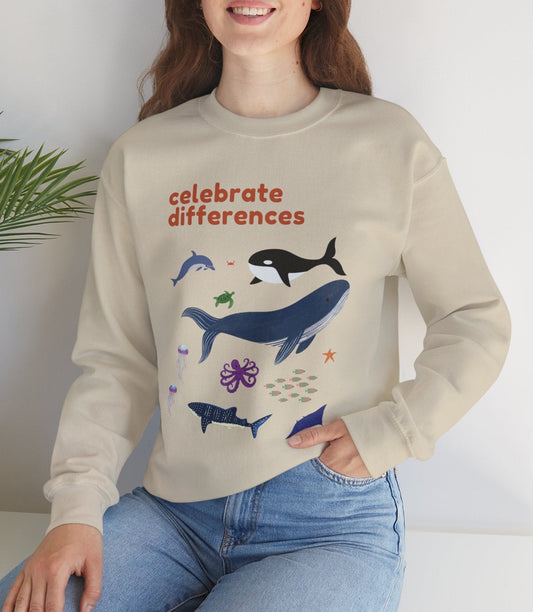 Person wearing a beige sweatshirt with whale illustrations and text, sitting on a white surface with a plant in the background.